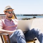 man working laptop beach chair