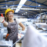 portrait female factory worker holding thumbs up