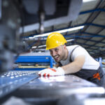 factory worker protective uniform hardhat operating industrial machine production line